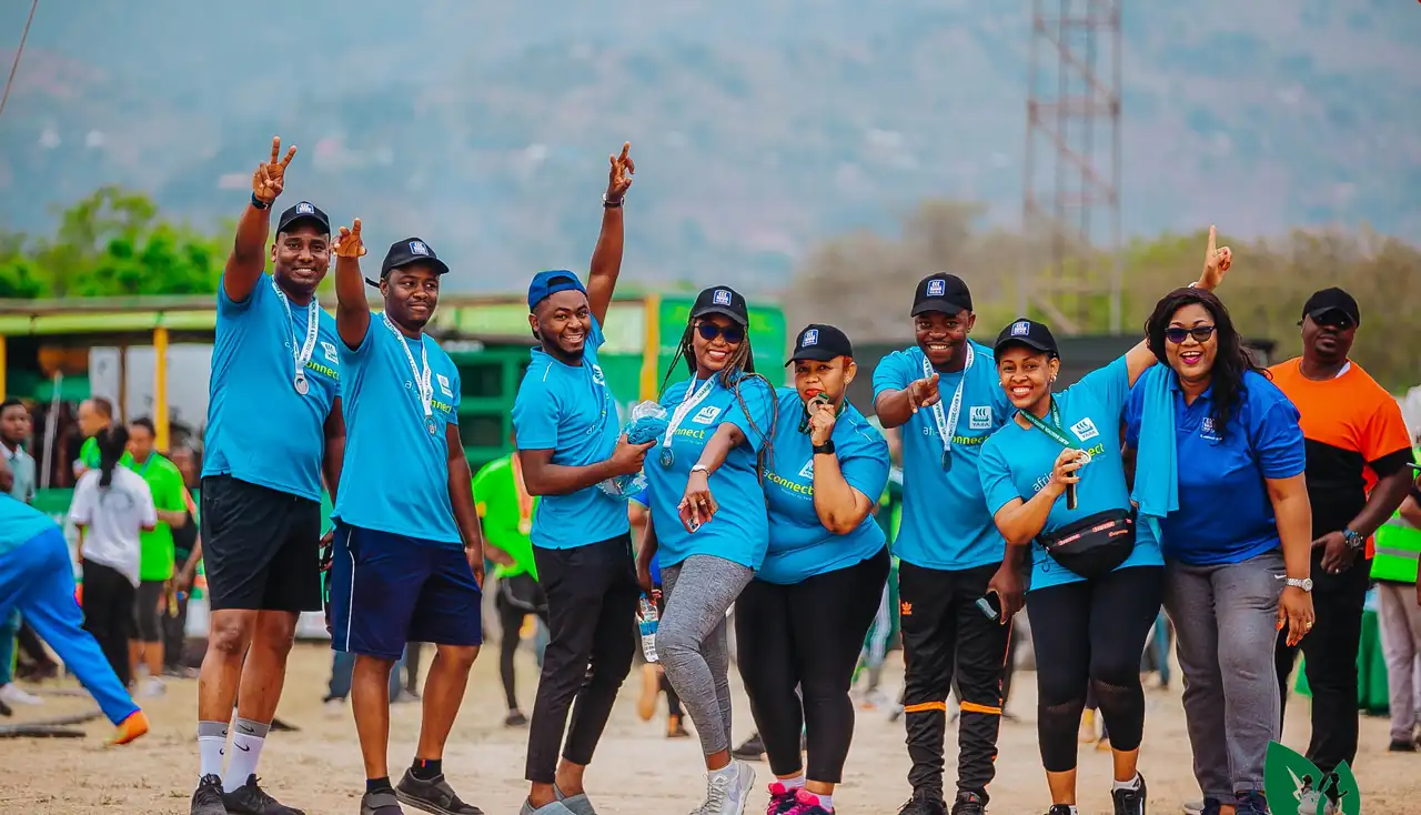 A team of runners in blue shirts celebrating with their medals
